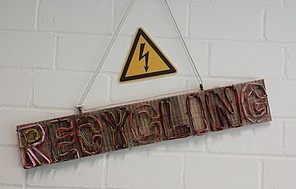Schief hängendes Holzschild mit der Aufschrift "Recycling"