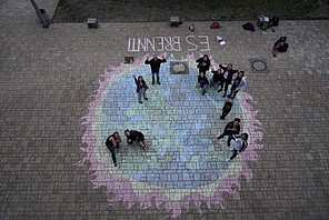 Schüler*innen des Mediencampus Babelsberg haben mit Kreide eine brennende Erde auf den Schulhof gemalt Schüler*innen des Mediencampus Babelsberg haben mit Kreide eine brennende Erde auf den Schulhof gemalt