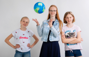 Drei Schülerinnen posieren mit einer Weltkugel